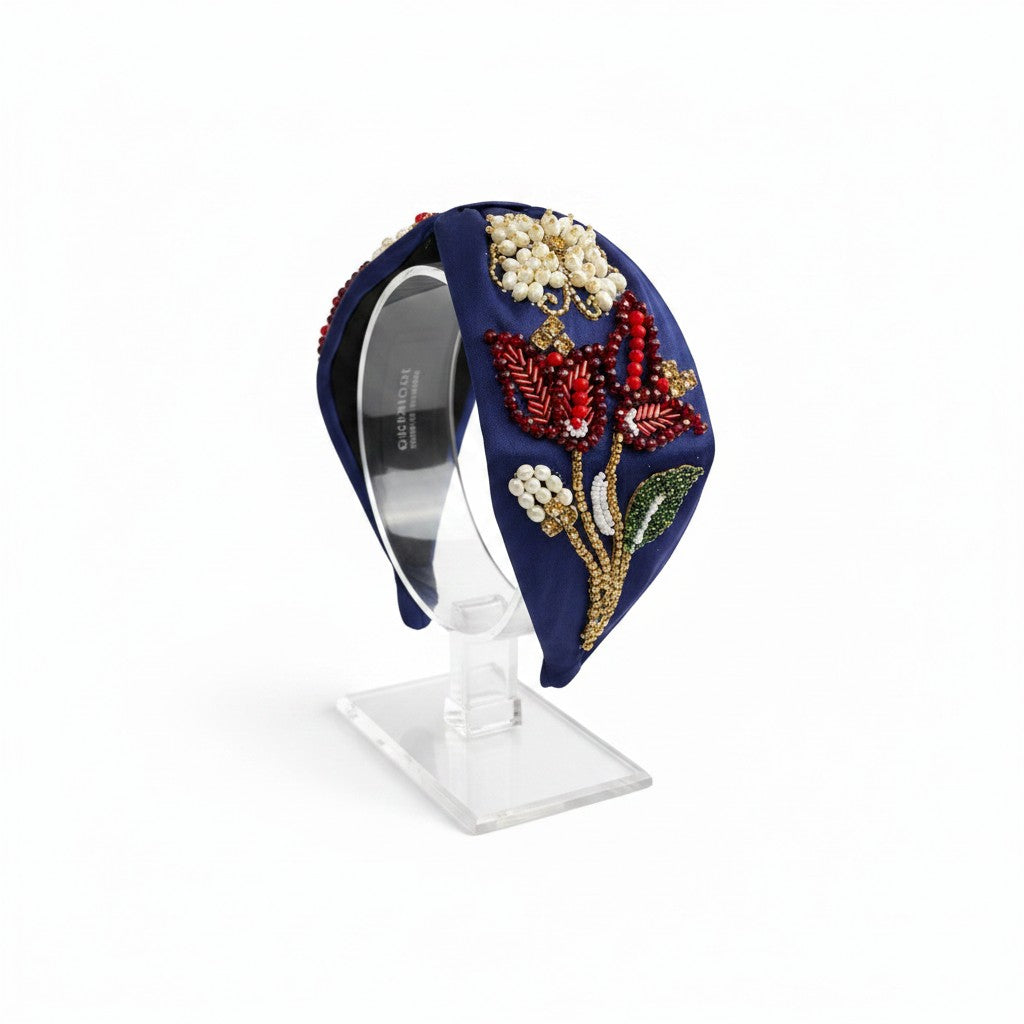 The Marigold Story navy blue headband featuring intricate red beaded floral motifs, pearl clusters, and gold crystals.