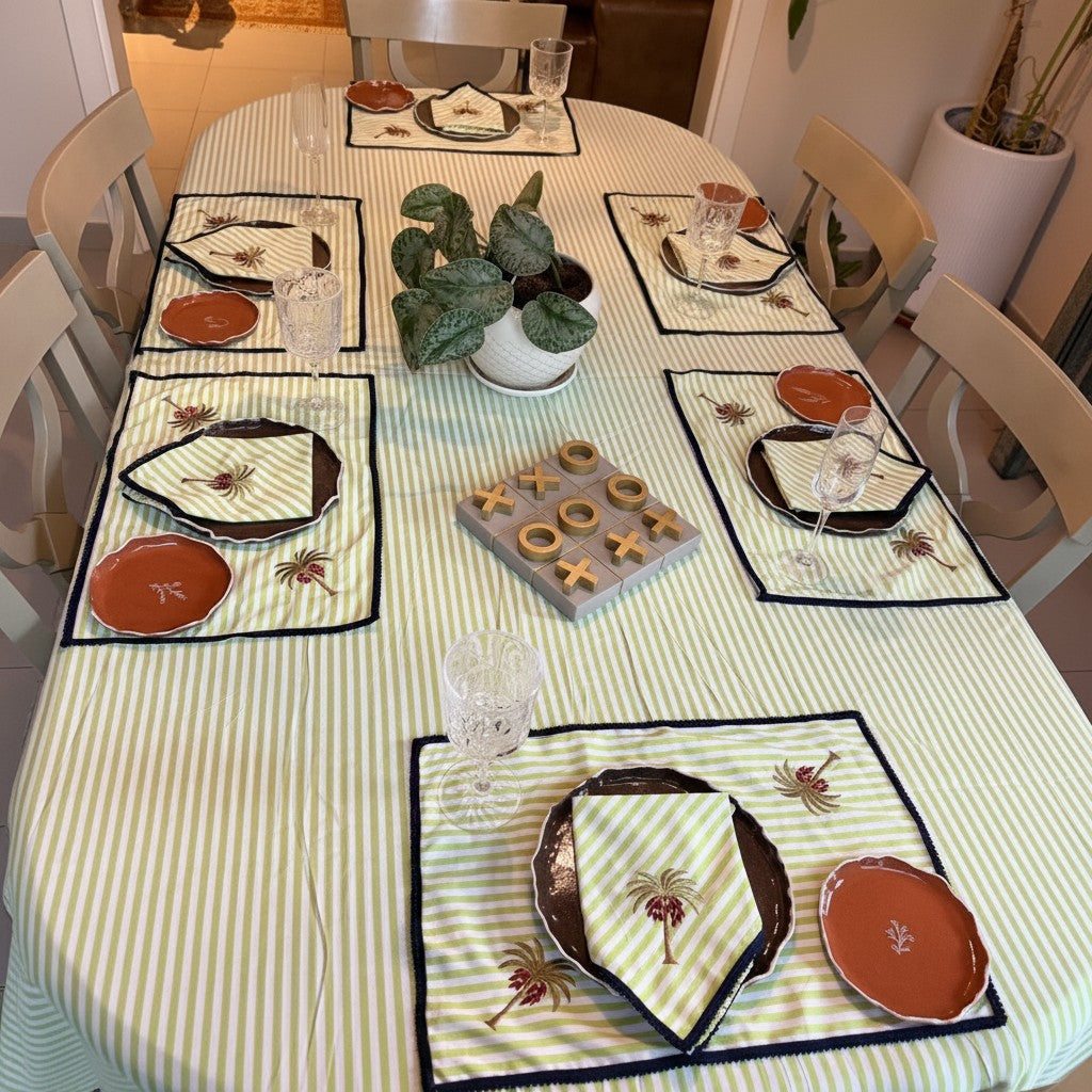 The Marigold Story handcrafted green striped tablecloth set with embroidered palm tree motifs and contrasting borders.