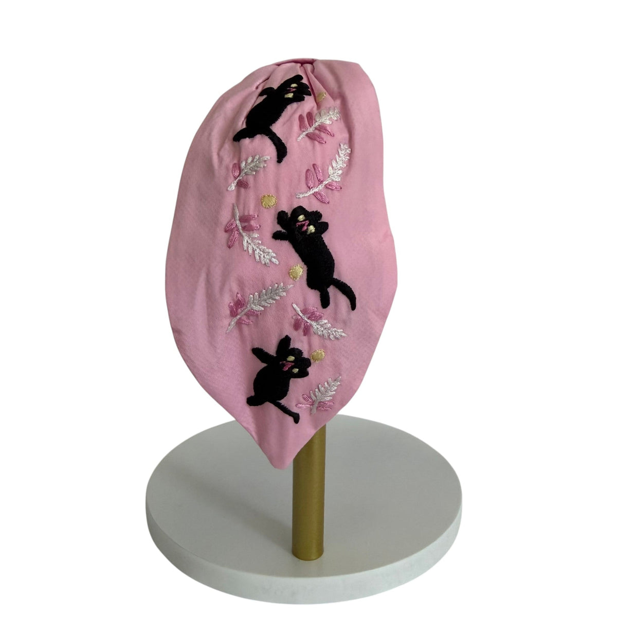 The Marigold Story pink padded headband featuring hand-embroidered black cats and silver botanical fern motifs.