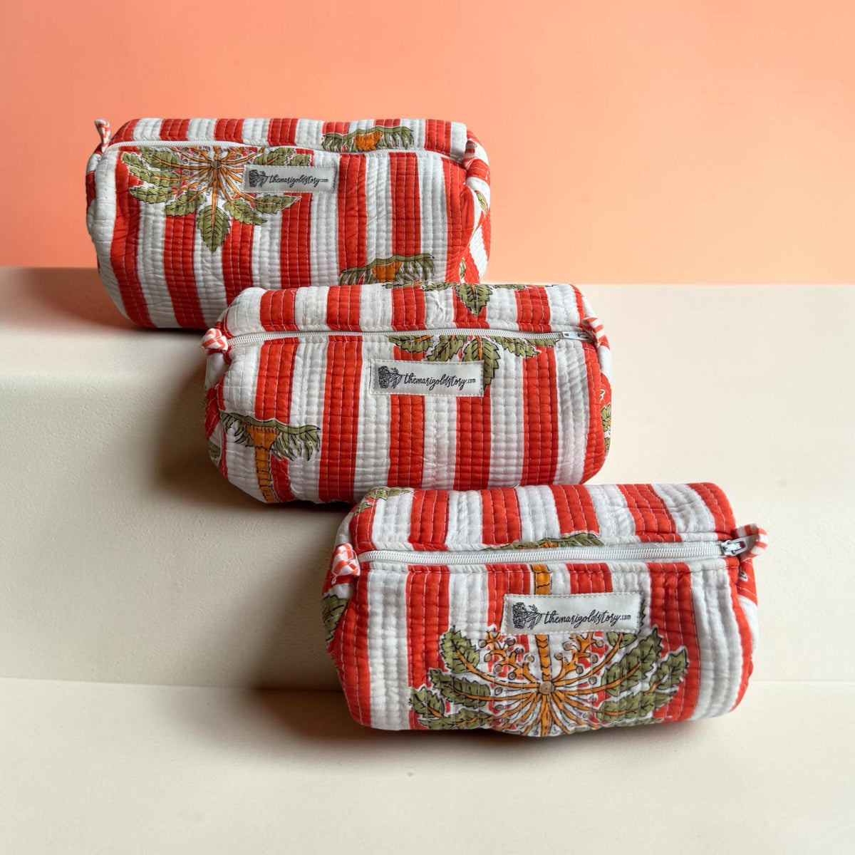 The Marigold Story set of three quilted cotton pouches with orange stripes and tropical hand-blocked palm prints.