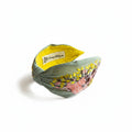 The Marigold Story sage green headband featuring hand-embroidered bird, pink flowers, and golden leaves