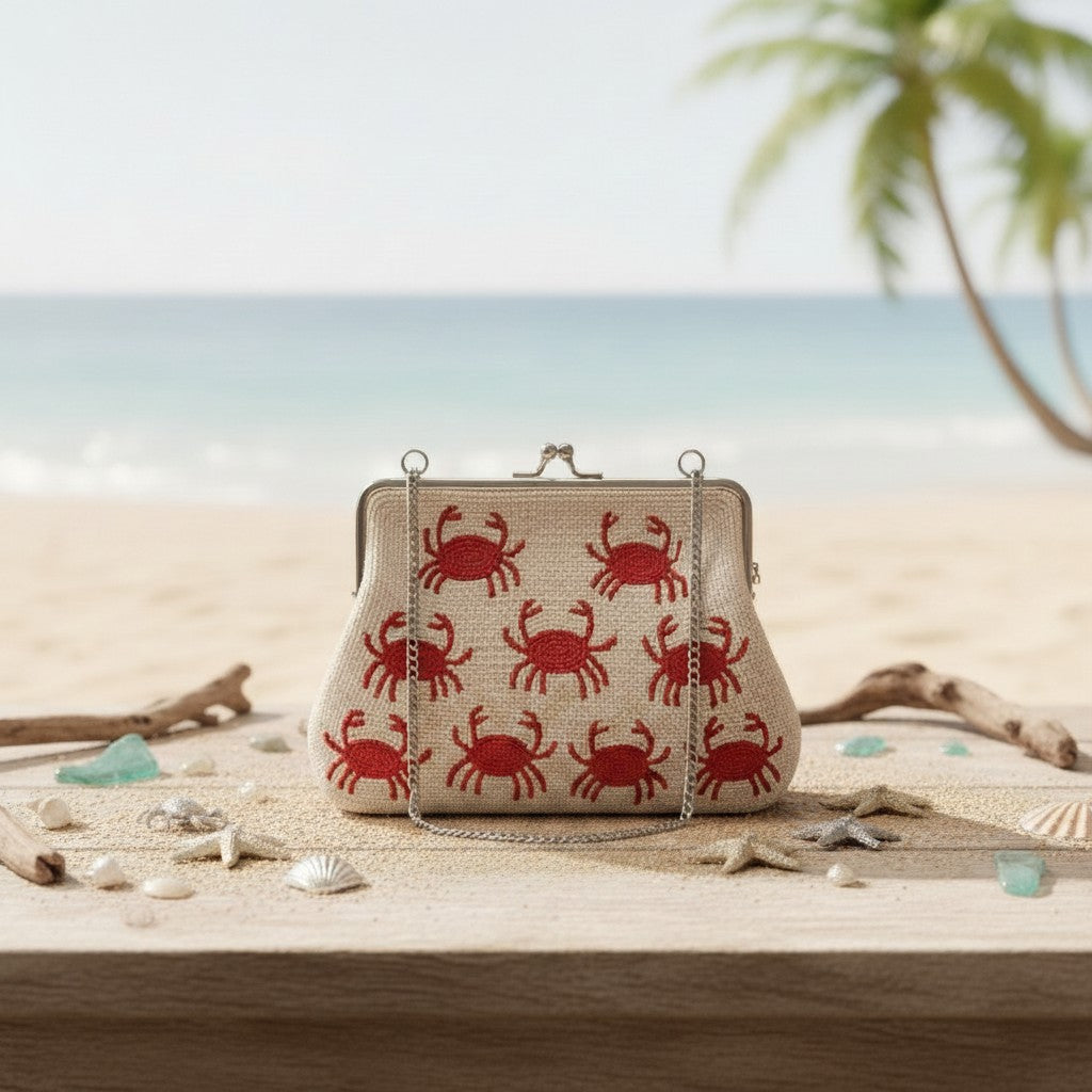 The Marigold Story white beaded sling bag with red crab motifs, featuring a metal frame and chain strap