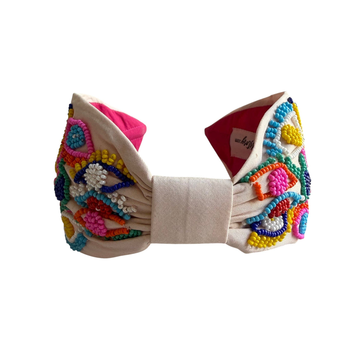 The Marigold Story handcrafted white headband featuring vibrant multicolor seed bead evil eye motifs and pink lining.